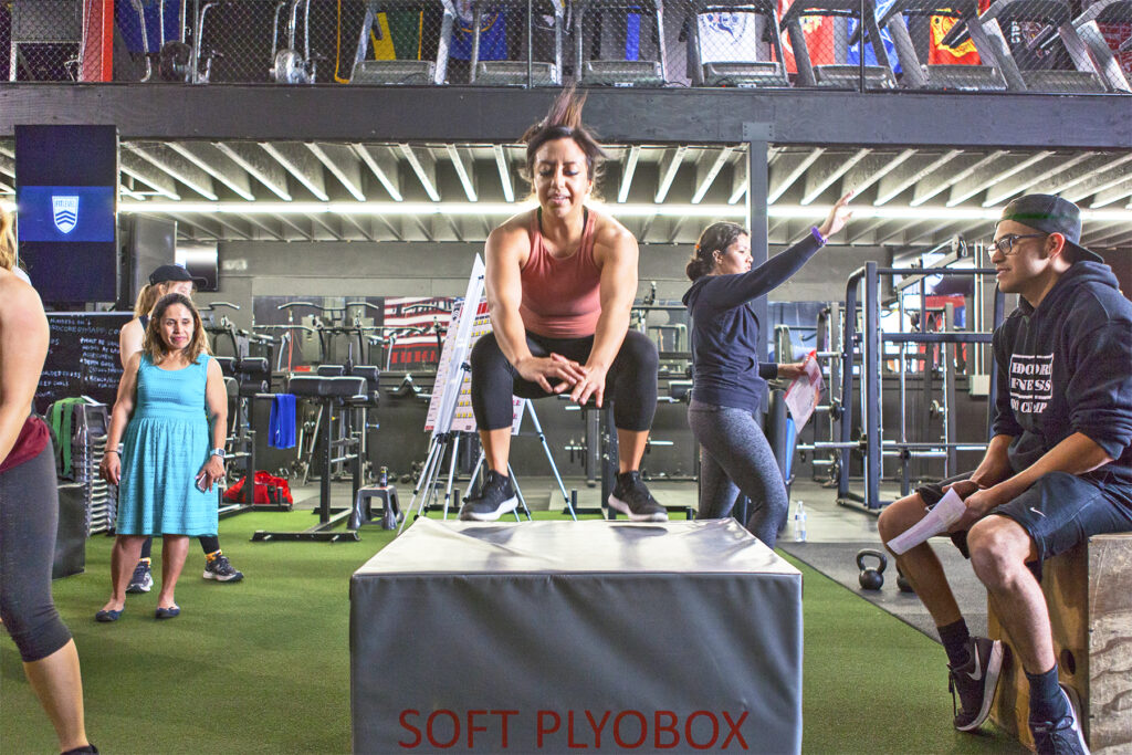 Fitness coach motivating participants during strength and cardio workout